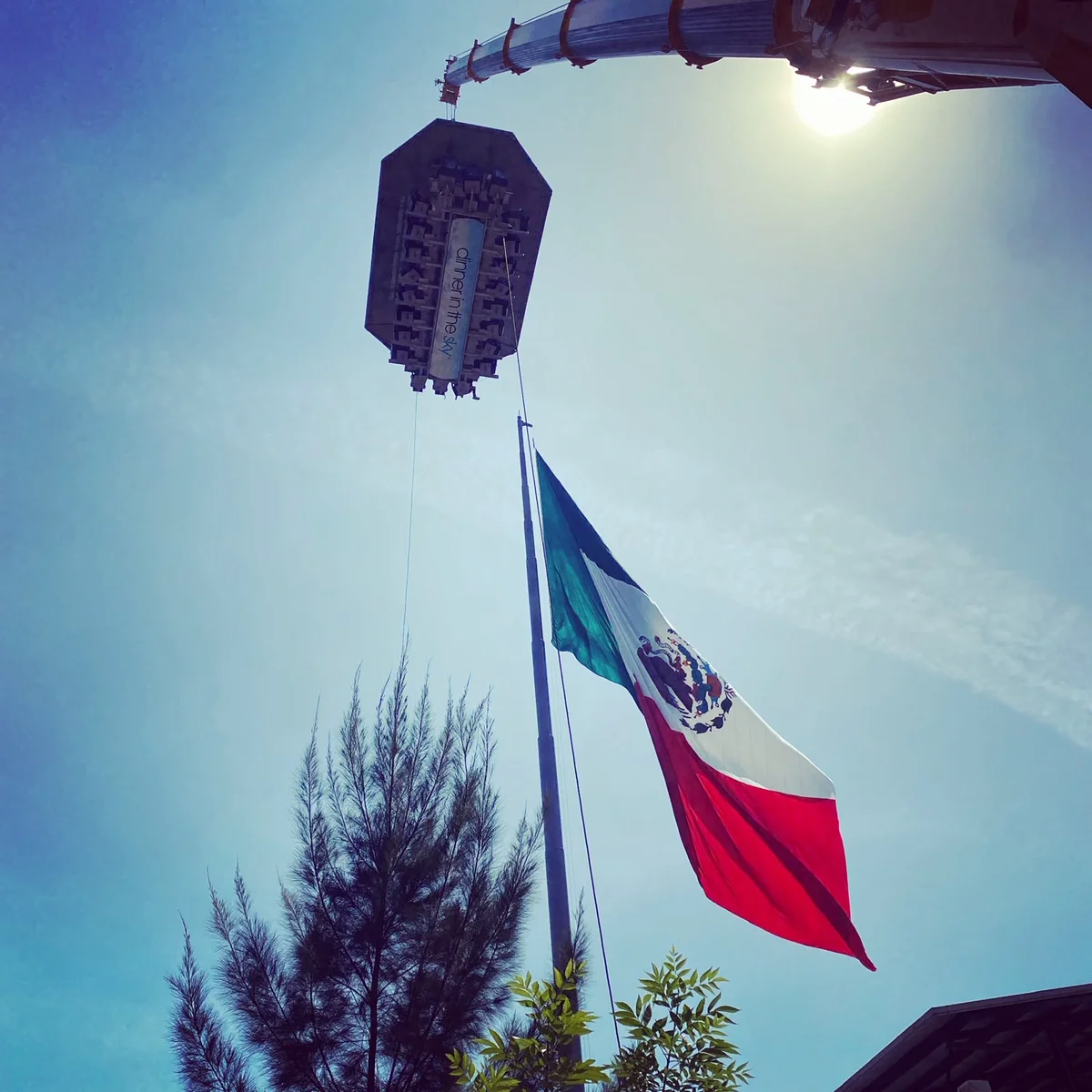 Mesa de Dinner in the Sky suspendida junto a la bandera de México